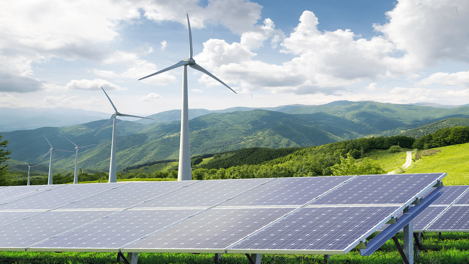 Photo of ground mount solar panels and wind turbines in the countryside