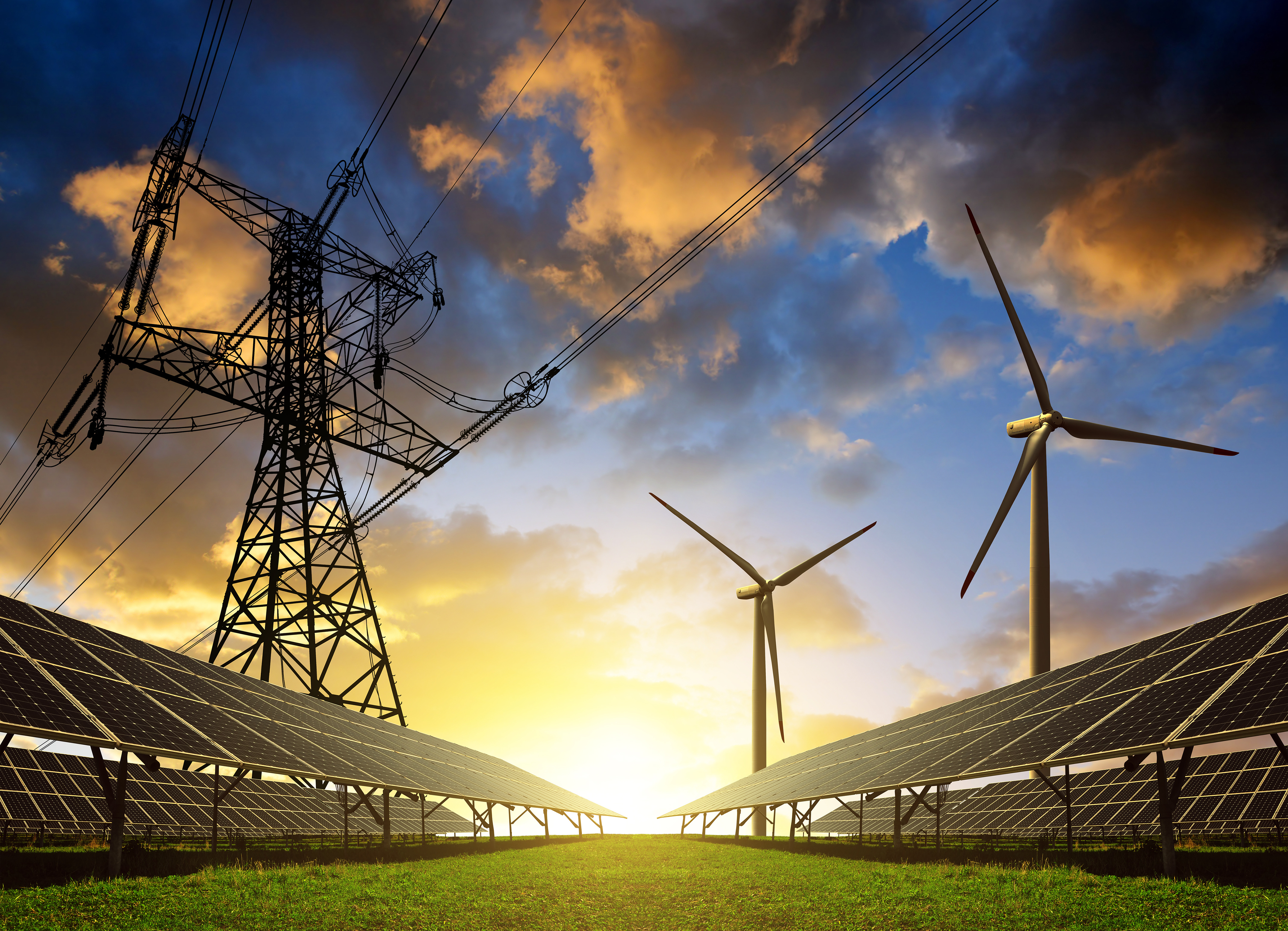 Photo of a solar panel installation with electricity pylons and wind turbines in the background