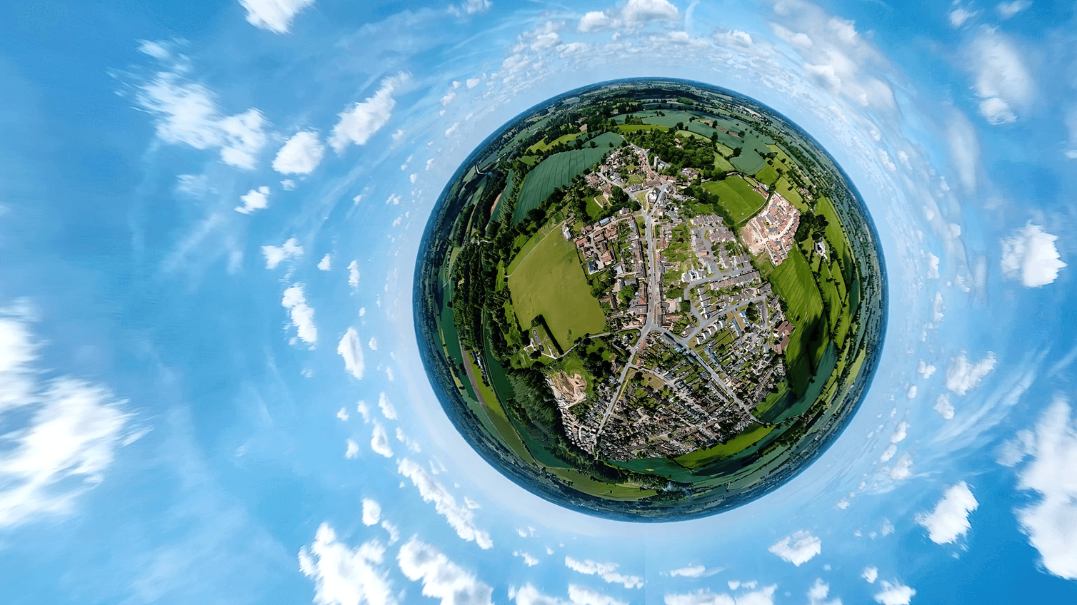 Photo of a town surrounded by fields and a blue sky